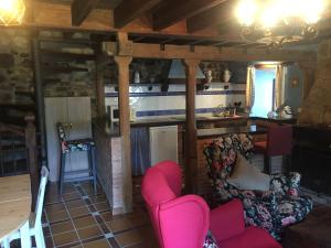 Casa rural Espinareu في Espinaredo: غرفة معيشة مع كراسي وردية ومطبخ