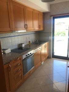 a kitchen with wooden cabinets and a sink and a stove at SOMAR Torre de Medronheira OLHOS DE AGUA ALBUFEIRA in Olhos de Água