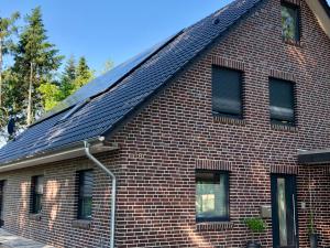 ein rotes Backsteinhaus mit Sonnenkollektoren auf dem Dach in der Unterkunft Ferienwohnung Hünzingen in Walsrode