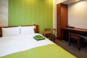 a bedroom with a bed and a desk with a green wall at Kitanoniwa The Kuretakeso in Hamamatsu
