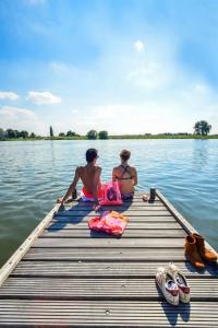 dwoje ludzi siedzących w doku w wodzie w obiekcie Boshotel Overberg w mieście Overberg