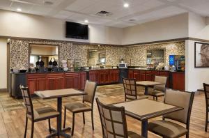 Best Western Plus Milwaukee Airport Hotel & Conference Center في ميلووكي: مطعم بطاولات وكراسي وكاونتر
