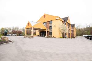a large yellow building with a large parking lot at Quality Inn Cromwell - Middletown in Cromwell