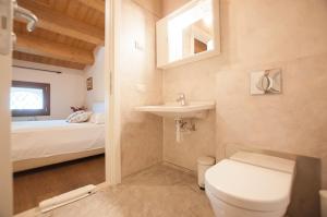 a bathroom with a toilet and a sink and a bed at La Costa in Sarcedo