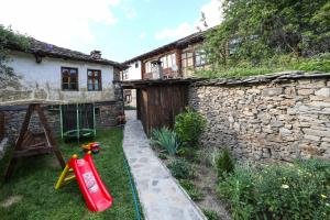a backyard with a stone building and a yard with a house at Тодорината къща in Leshten