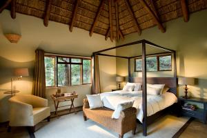 a bedroom with a bed and a chair and windows at Letlapa Pula Game Farm in Leeupoort