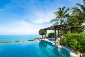 a swimming pool with a gazebo next to the ocean at The Jungle Club - SHA Extra Plus in Chaweng Noi Beach