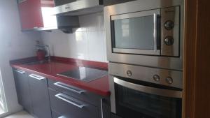 - une cuisine équipée d'un four micro-ondes et d'un comptoir rouge dans l'établissement Precioso apartamento, à Lugo