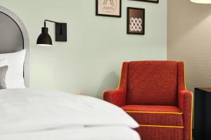 Schlafzimmer mit einem roten Stuhl und einem Bett in der Unterkunft MAXX Hotel Sanssouci Potsdam in Potsdam