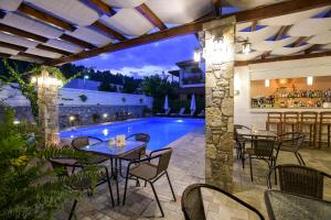 a patio with tables and chairs next to a swimming pool at Neda Hotel in Olympia