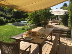 a wooden table and chairs on a deck with an umbrella at villa Sant-Anna in Saint-Tropez