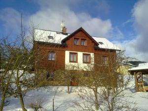 a large wooden house in the snow at Apartment Rokys in Rokytnice nad Jizerou