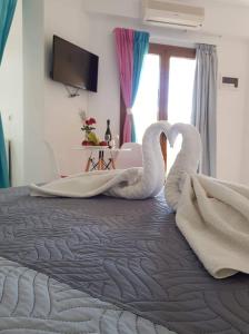 two swans laying on top of a bed at Vrisi Apartments & Villa in Pitsidia