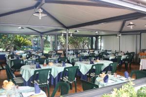 a dining room with tables and chairs with blue napkins at Hotel Rosalia in Bordighera