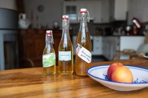 drei Flaschen Essig und eine Schale Obst auf dem Tisch in der Unterkunft Domaine de la Coteire in Cugy