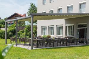 a patio with tables and chairs in a yard at Hotel Max 70 in Salzburg