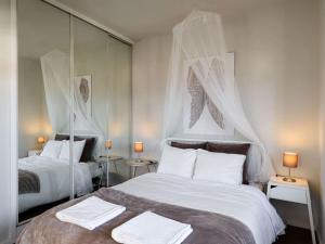 a bedroom with two beds with white sheets and mirrors at Carcavelos Beach&Bike House (view, parking, wi-fi) in Carcavelos