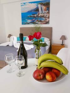 een tafel met een fruitschaal en een fles wijn bij Vrisi Apartments & Villa in Pitsidia