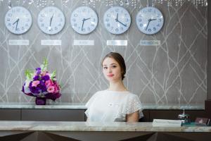 Una donna in piedi a un bancone con gli orologi sul muro di Crystal Hotel a Kiev