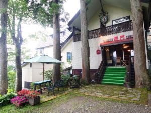 a building with a bench and an umbrella and trees at Hotel Mumon in Myoko