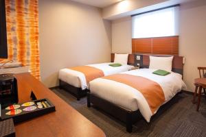 浜松市にある北の庭 THE KURETAKESOのベッド2台とテレビが備わるホテルルームです。