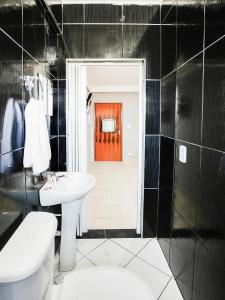 uma casa de banho com um lavatório branco e uma porta vermelha em OYO Hotel Boneville, São Paulo em São Paulo
