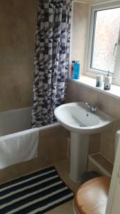 ein Bad mit einem Waschbecken und einem Duschvorhang in der Unterkunft Gateshead's Amethyst 3 Bedroom Apt, Sleeps 6 Guests in Gateshead