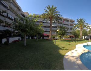 un gran edificio de apartamentos con palmeras y una piscina en Cambrils Regata Apartamento junto el mar en Cambrils