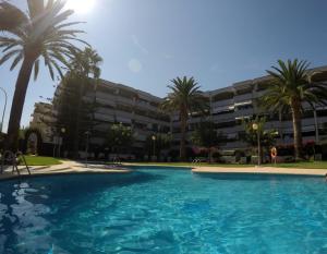 een zwembad voor een gebouw met palmbomen bij Cambrils Regata Apartamento junto el mar in Cambrils