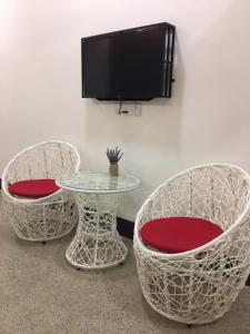 three chairs and a table with a tv on a wall at Sunshine Lodge in Kuantan