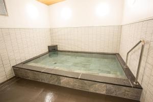 a bath tub in a room with white tiles at Kitanoniwa The Kuretakeso in Hamamatsu