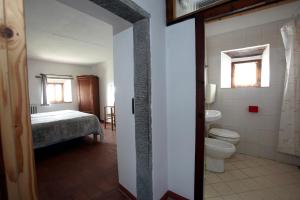 a bathroom with a toilet and a bed in a room at Casina Della Burraia in Subbiano