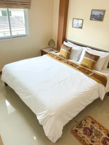 a large white bed in a bedroom with a window at Baan Sooksiri Bangsaray in Bang Sare