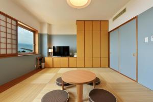 葉山町にある葉山 うみのホテルのテーブル、椅子2脚、テレビが備わる客室です。