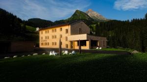 un edificio con sillas frente a él con una montaña en Am Gehren - Arlberg Appartements, en Warth am Arlberg