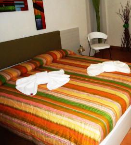 a bed with a colorful blanket and white towels on it at Ciuscia in Calatabiano