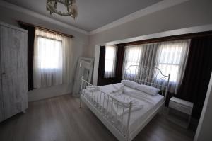 a bedroom with a white bed and two windows at Queen Bee Hotel in Selçuk
