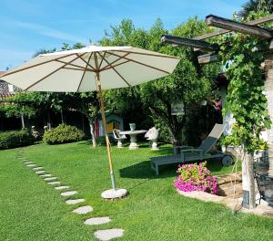 an umbrella in a yard with a bench and a table at La Pergola B&B in Cesena