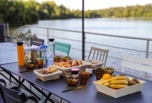 a table with bread and other food on it next to the water at La Rivière House - Péniche Carpe Diem in Nantes