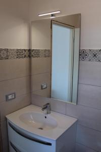 La salle de bains est pourvue d'un lavabo et d'un miroir. dans l'établissement Home Holiday Punta Piccola, à Porto Empedocle