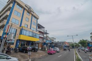 una calle de la ciudad con coches aparcados en el lateral de un edificio en RedDoorz Syariah at Grand Taufiq Tarakan en Tarakan