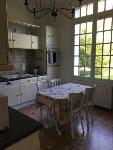 una cucina con tavolo, sedie e finestre di L'Hermitage a Saint-Martin-des-Champs