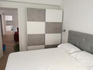 1 dormitorio con cama blanca y cabecero gris en Zapillo, en Almería
