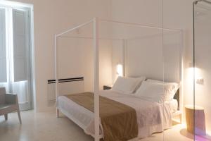 uma cama branca com um dossel de vidro num quarto em Donna Domenica Boutique Suites em Polignano a Mare