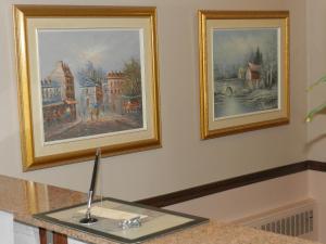 two framed paintings on a wall with a table at L'Auberge de l'Aeroport Inn in Dorval