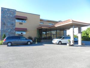 two cars parked in a parking lot in front of a building at L'Auberge de l'Aeroport Inn in Dorval