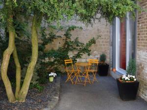 eine Terrasse mit einem Tisch, Stühlen und einem Baum in der Unterkunft Le Pavillon de Nathalie in Isles-sur-Suippe
