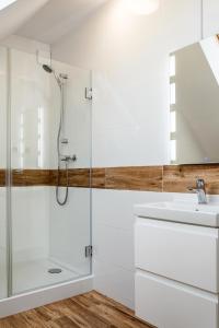 a white bathroom with a shower and a sink at Nowe komfortowe domki Albatros in Łeba +57 photos