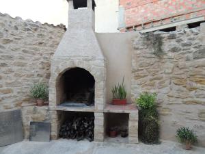 un horno al aire libre con una pared de piedra y plantas en Las Bodegas Del Gilo, en Valdealgorfa