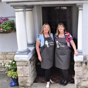 Due donne in piedi sulla porta di una casa di Swanage Haven Boutique Guest House a Swanage